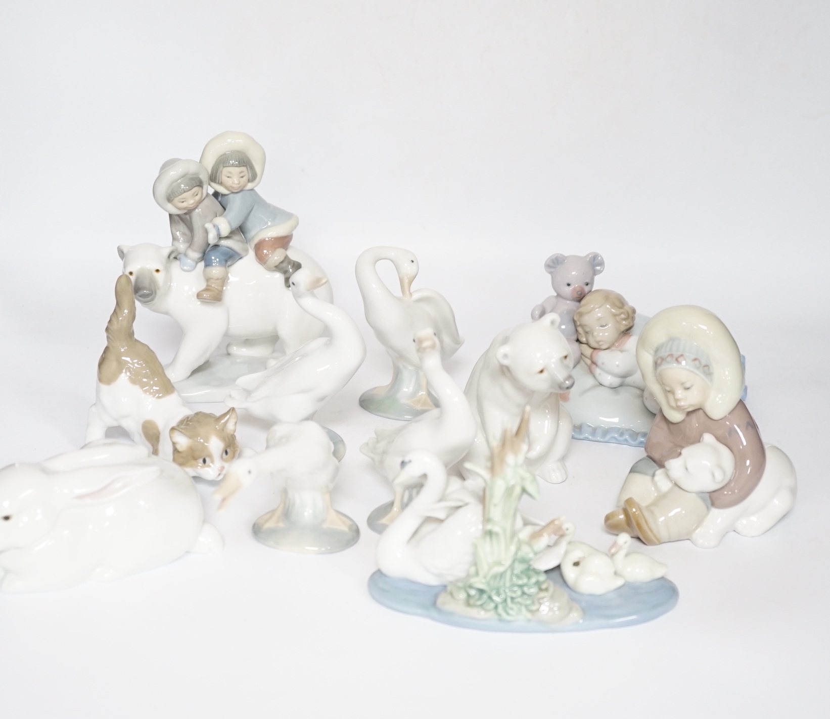 Eleven Lladro figure groups, including a collection of ducks, two Eskimo figure groups, a sleeping child with teddy on a cushion etc, none boxed